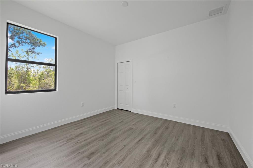 369 Ranier Avenue Lehigh Acres, FL 33974 - Photo 16 of 22 a view of an empty room with wooden floor and a painting on the wall