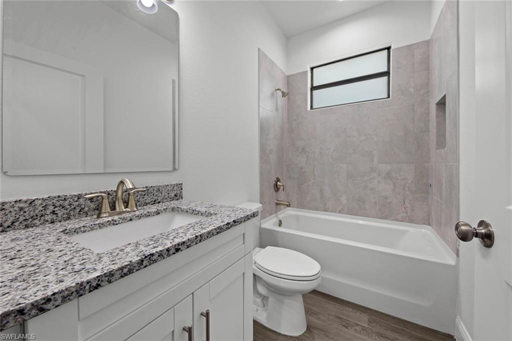369 Ranier Avenue Lehigh Acres, FL 33974 - Photo 17 of 22 a bathroom with a granite countertop sink a toilet and bathtub