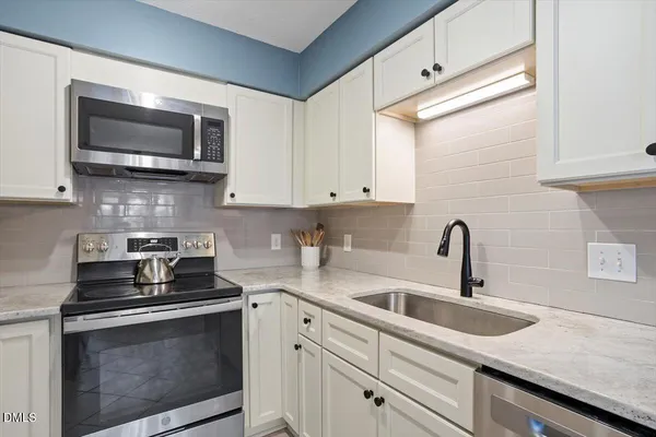 a kitchen with stainless steel appliances granite countertop a sink a stove a microwave and cabinets
