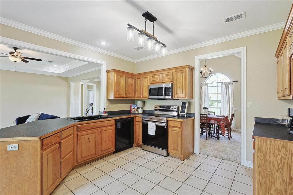 3289 Mitchell Road Krum, TX 76249 - Photo 10 of 40 a kitchen with stainless steel appliances granite countertop a stove top oven a sink dishwasher a dining table and chairs with wooden floor