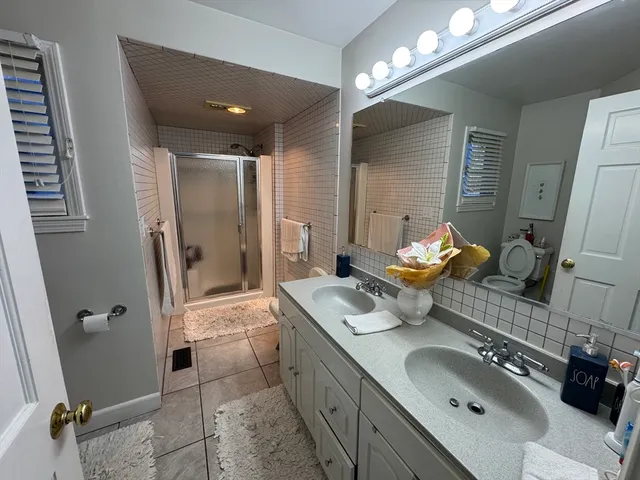 a bathroom with a granite countertop double vanity sink a mirror and a shower