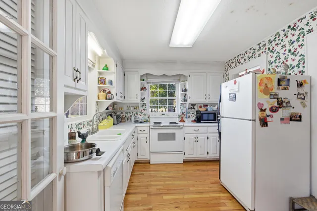 a kitchen with a refrigerator a stove a sink and a window with wooden floor