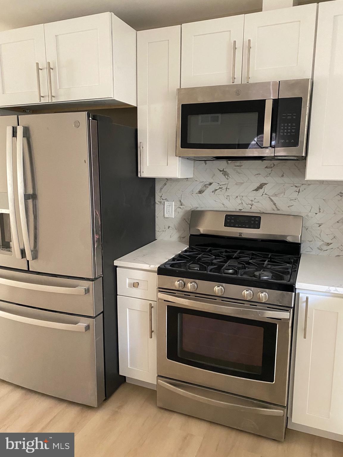 6445 Garman Street Philadelphia, PA 19142 - Photo 8 of 56 a kitchen with stainless steel appliances white cabinets a stove a microwave and a refrigerator