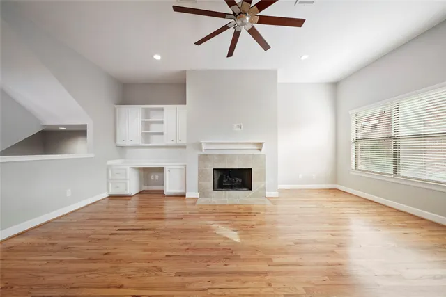 an empty room with windows fireplace and wooden floor