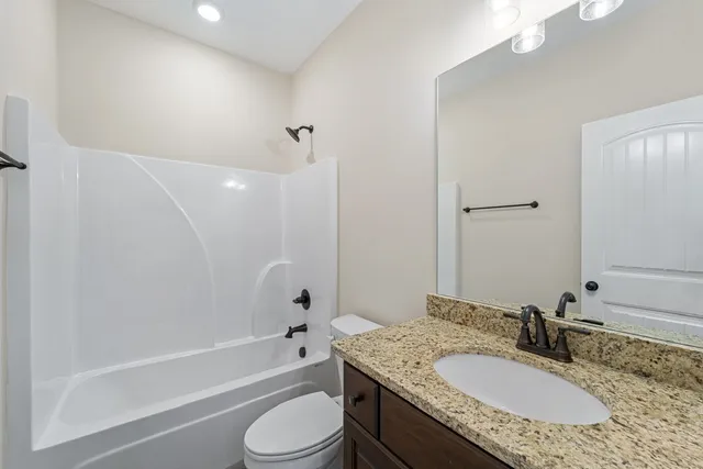 a bathroom with a granite countertop tub sink toilet shower and mirror