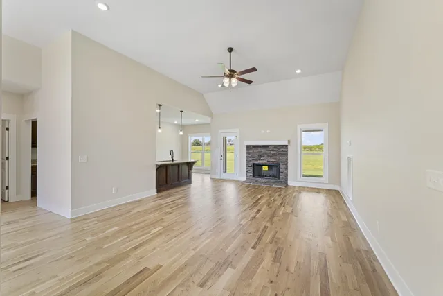 a view of a livingroom with a fireplace a ceiling fan and wooden floor