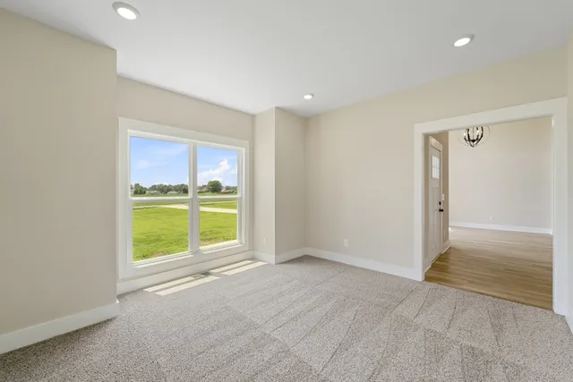 a view of an empty room with a window and a kitchen