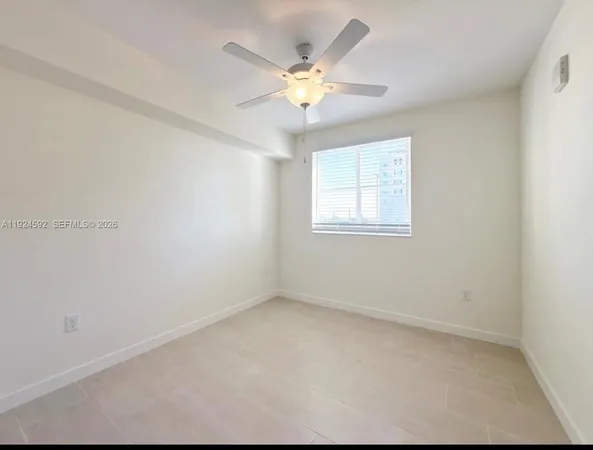 an empty room with chandelier fan and windows