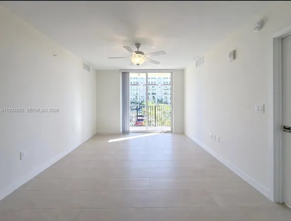 an empty room with windows and chandelier fan