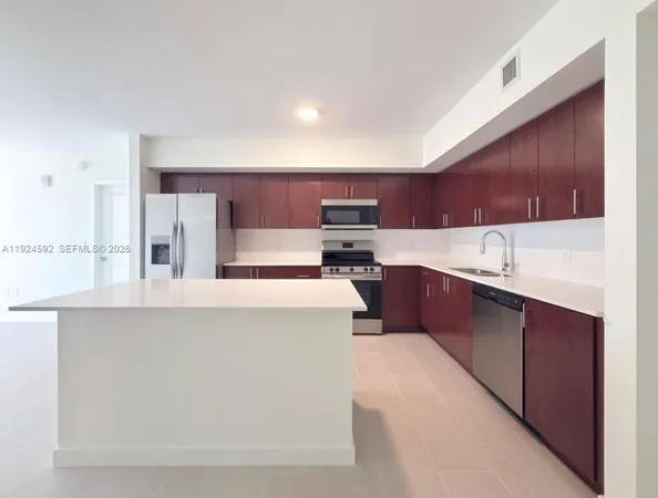 a kitchen with kitchen island a sink a stove a refrigerator cabinets and a counter top space