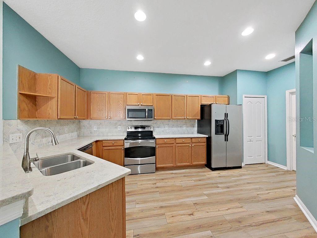 6077 Sandhill Ridge Drive Lithia, FL 33547 - Photo 8 of 58 a kitchen with stainless steel appliances a sink a stove a refrigerator cabinets and wooden floor