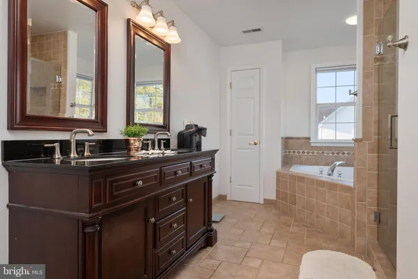 a bathroom with a sink vanity granite tub and a mirror