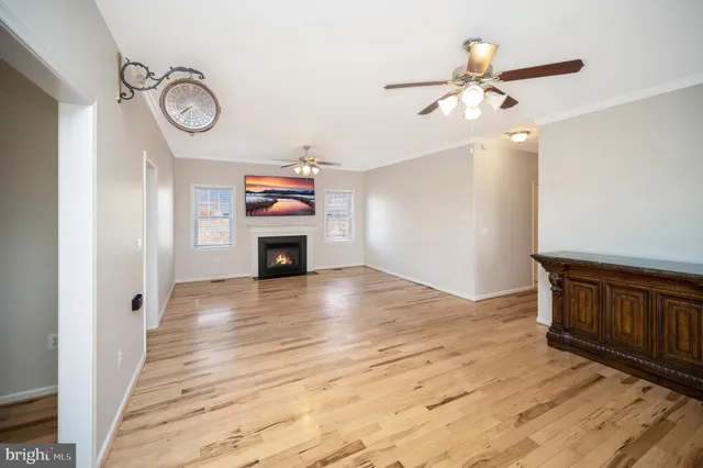 a view of an empty room with wooden floor fireplace and a window