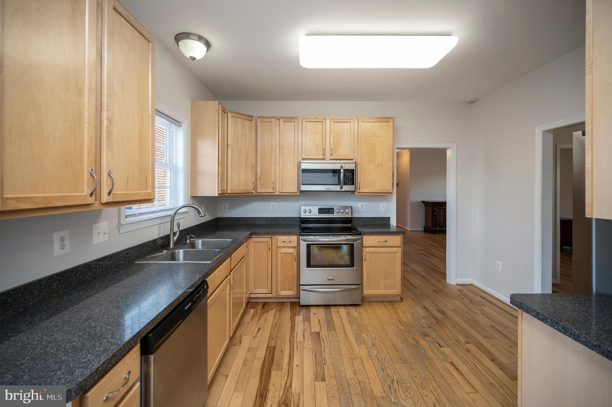 773 Truslow Road Fredericksburg, VA 22406 - Photo 31 of 63 a kitchen with granite countertop wooden floors stainless steel appliances a sink and a window
