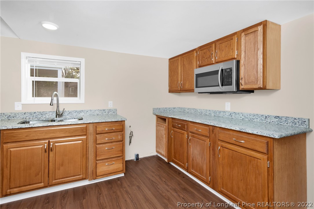 6129 Fisher Road Fayetteville, NC 28306 - Photo 12 of 31 a kitchen with stainless steel appliances granite countertop a sink a microwave cabinets and a wooden floor