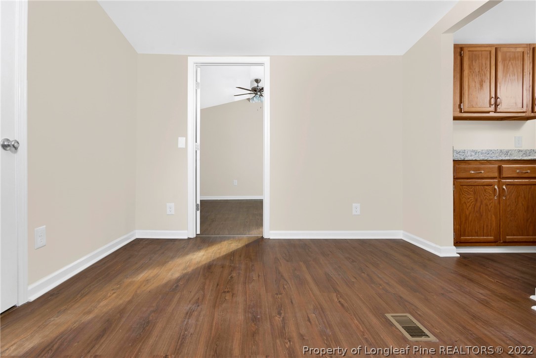 6129 Fisher Road Fayetteville, NC 28306 - Photo 10 of 31 an empty room with wooden floor and cabinet