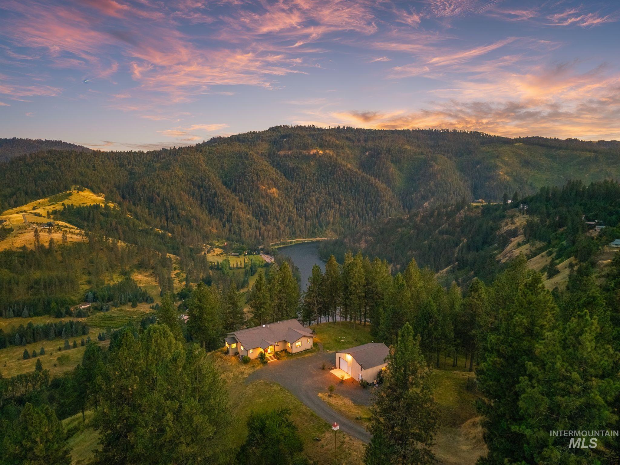 435 River Pointe Lane Lenore, ID 83541 - Photo 31 of 50 Expansive property featuring two structures, dense mature evergreen trees, and a clear blue river winding through a mountainous landscape