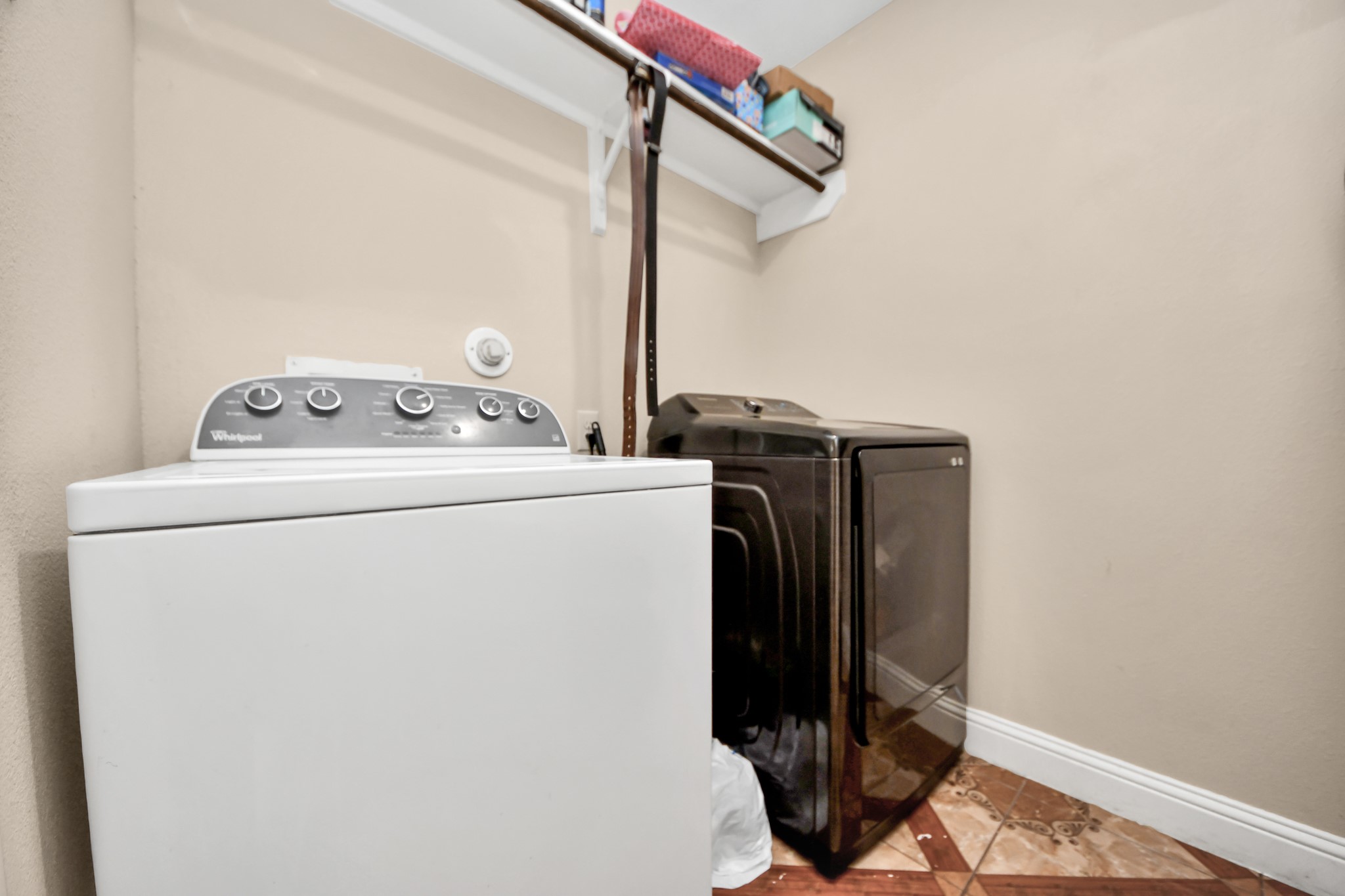 9250 Strawberry Cactus Loop Houston, TX 77064 - Photo 24 of 26 Spacious laundry room featuring modern washer and dryer, with upper shelving for convenient storage.