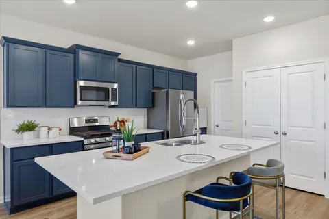 a kitchen with stainless steel appliances a refrigerator a stove a sink a dining table and chairs