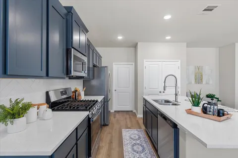 a kitchen with stainless steel appliances a sink a stove cabinets and wooden floor