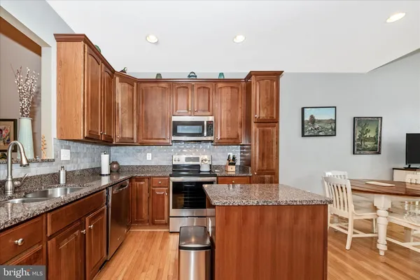 a kitchen with granite countertop a stove top oven a sink dishwasher a dining table and chairs with wooden floor