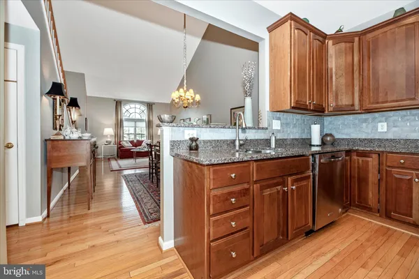a kitchen with granite countertop a refrigerator stove top oven dining table and wooden floor