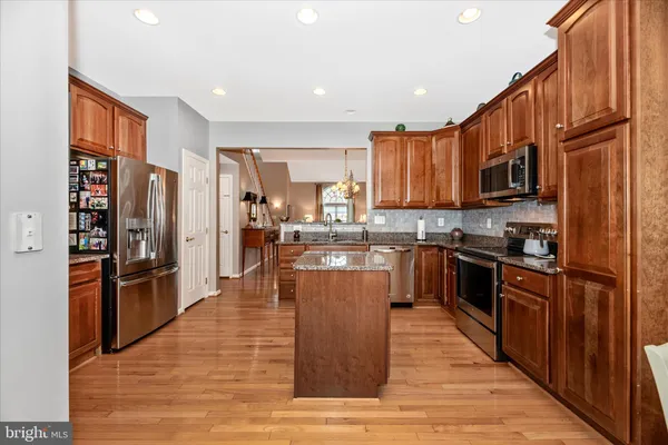 a kitchen with stainless steel appliances granite countertop a refrigerator and wooden cabinets