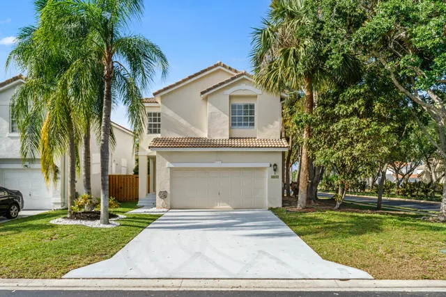 a view of house with a yard and palm trees