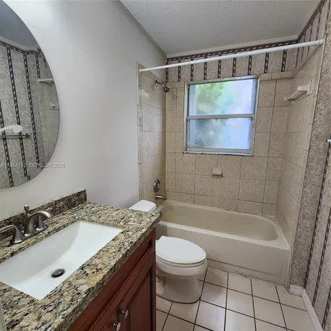 a bathroom with a granite countertop sink a toilet and shower