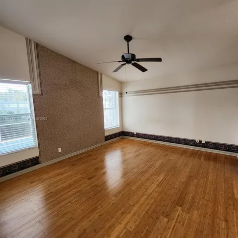a view of empty room with wooden floor and fan