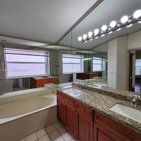 a bathroom with a granite countertop sink a large mirror and a bathtub