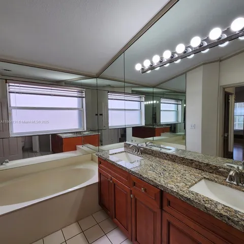 a bathroom with a granite countertop sink a large mirror and a bathtub