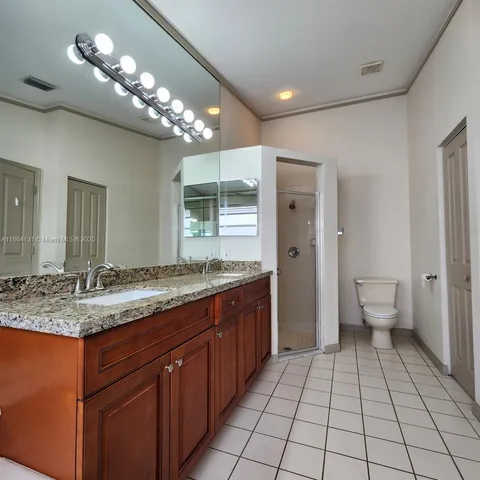 a bathroom with a granite countertop sink a toilet and a large mirror