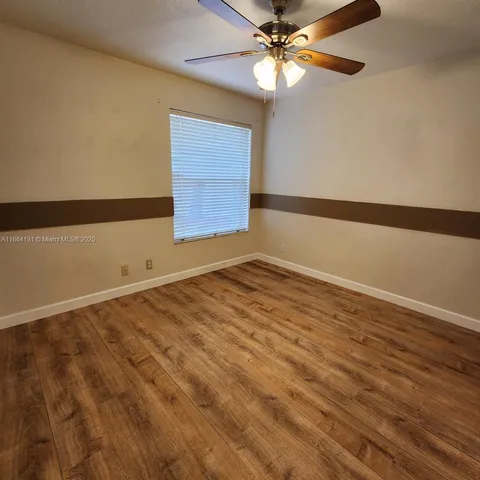 a view of an empty room with window and chandelier fan