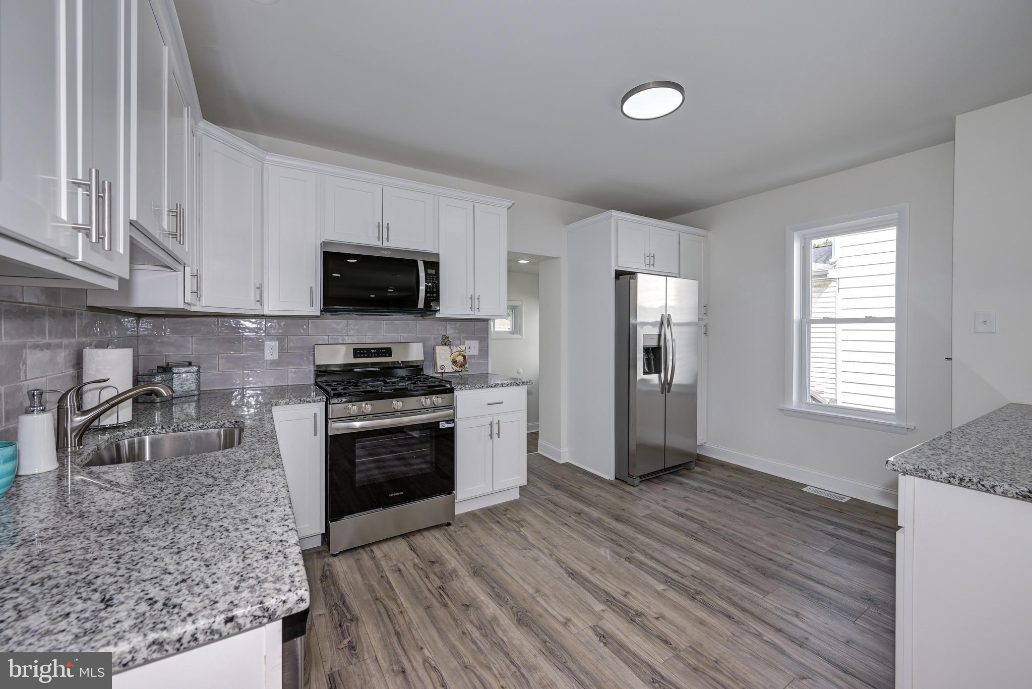 304 Cleveland Avenue Riverside, NJ 08075 - Photo 14 of 35 a kitchen with granite countertop a stove top oven a sink dishwasher a refrigerator and a microwave oven with wooden floor