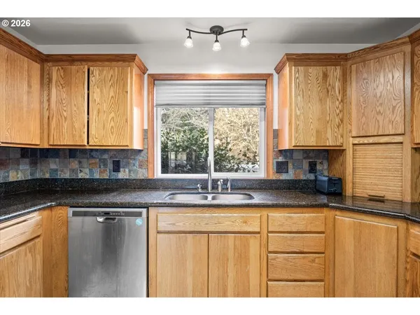 a kitchen with a window a sink dishwasher a refrigerator and cabinets