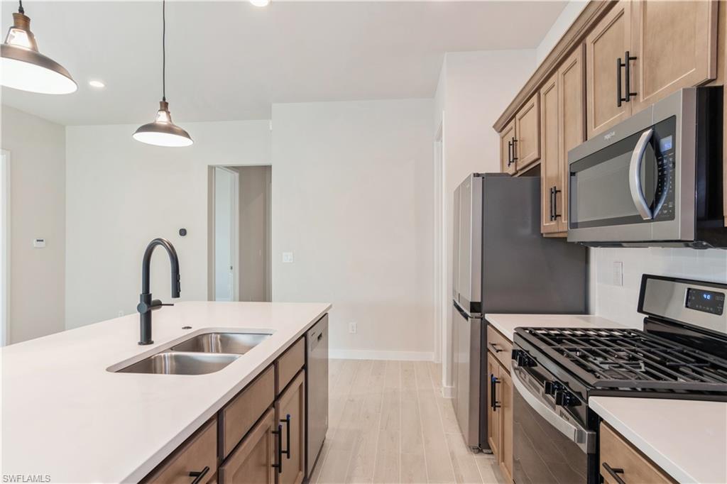 14867 Loggerhead Drive Naples, FL 34120 - Photo 3 of 21 a kitchen with stainless steel appliances granite countertop a sink dishwasher a stove and a refrigerator with wooden floor