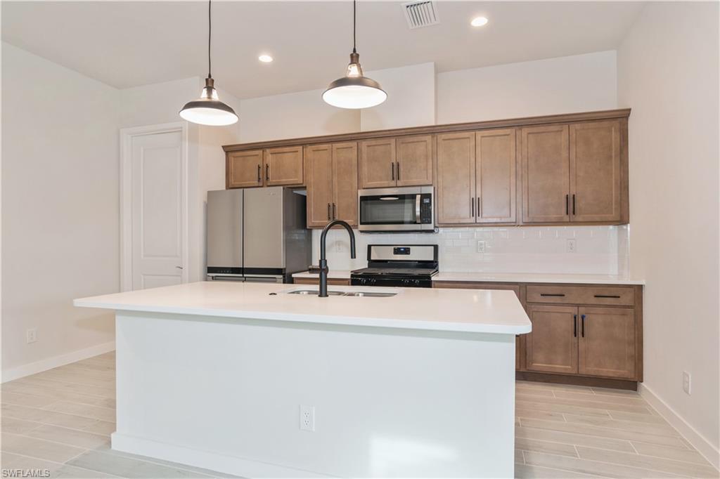 14867 Loggerhead Drive Naples, FL 34120 - Photo 5 of 21 a kitchen with kitchen island a sink stainless steel appliances and cabinets