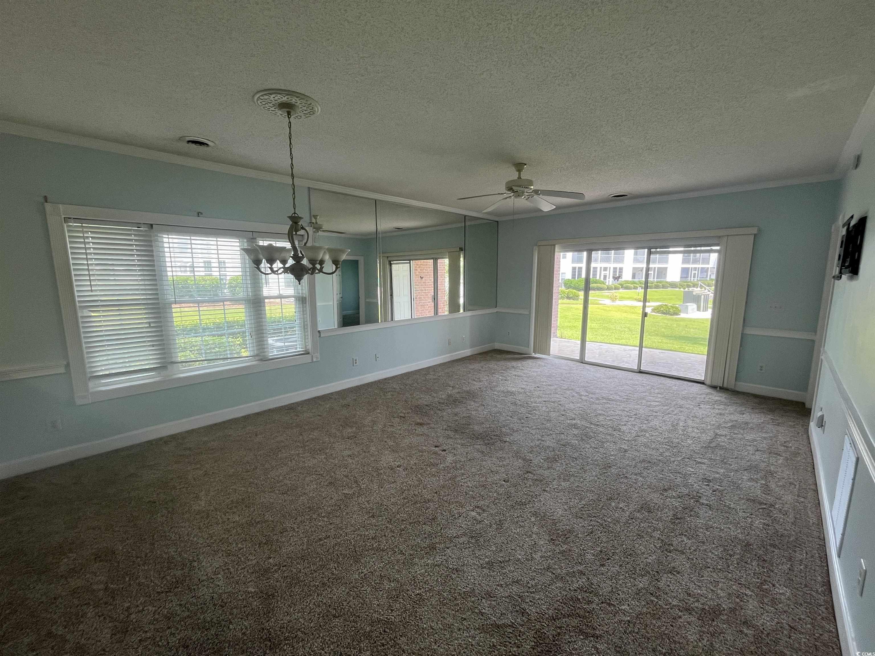 1514 Lanterns Rest Road, Unit 101 Myrtle Beach, SC 29579 - Photo 14 of 20 Unfurnished dining area featuring crown molding, healthy amount of natural light, a ceiling fan, carpet floors, and a textured ceiling