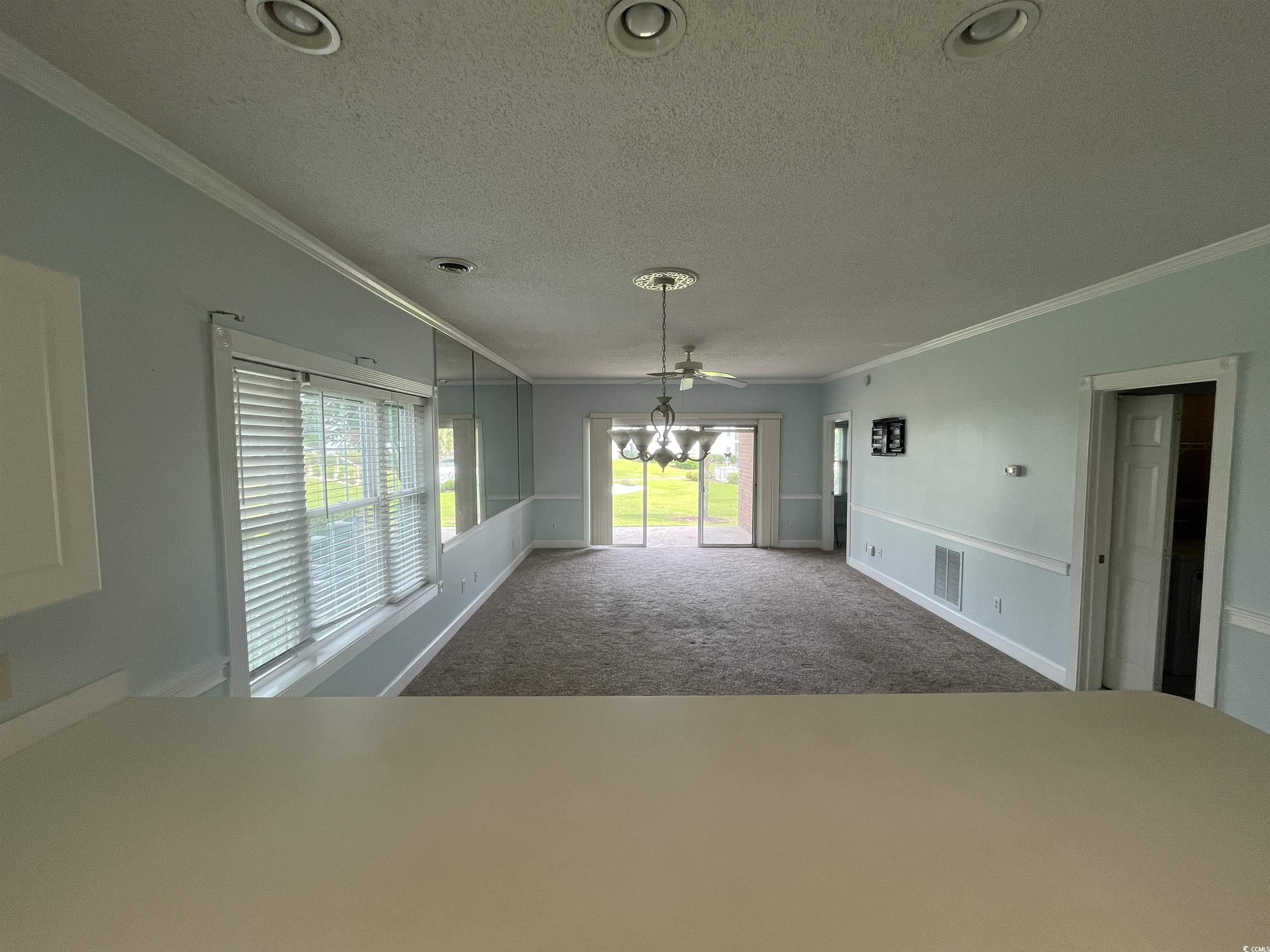 1514 Lanterns Rest Road, Unit 101 Myrtle Beach, SC 29579 - Photo 16 of 20 Unfurnished living room featuring a textured ceiling, carpet floors, ornamental molding, a chandelier, and recessed lighting