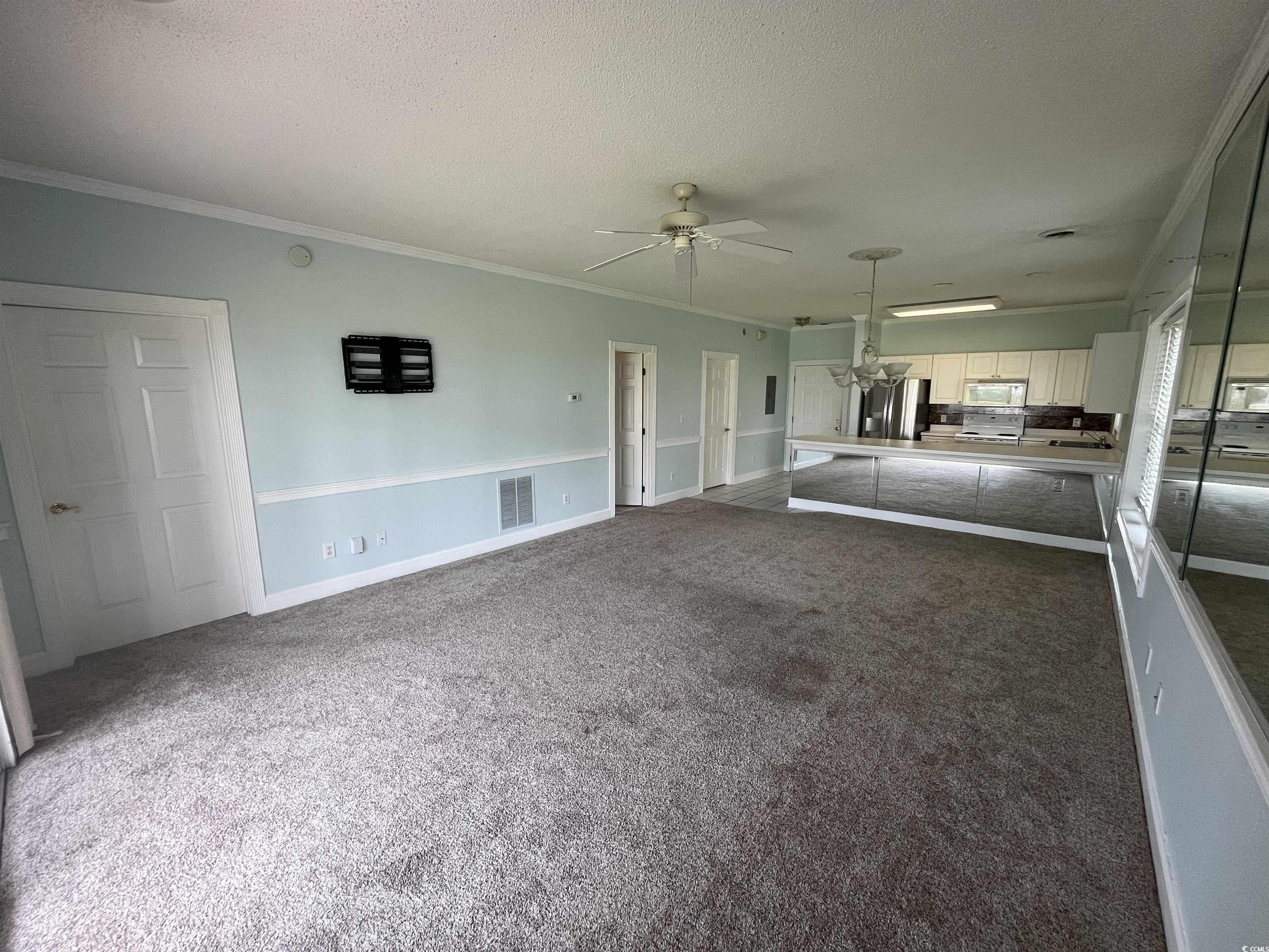 1514 Lanterns Rest Road, Unit 101 Myrtle Beach, SC 29579 - Photo 20 of 20 Unfurnished living room featuring ceiling fan, ornamental molding, carpet flooring, and a textured ceiling