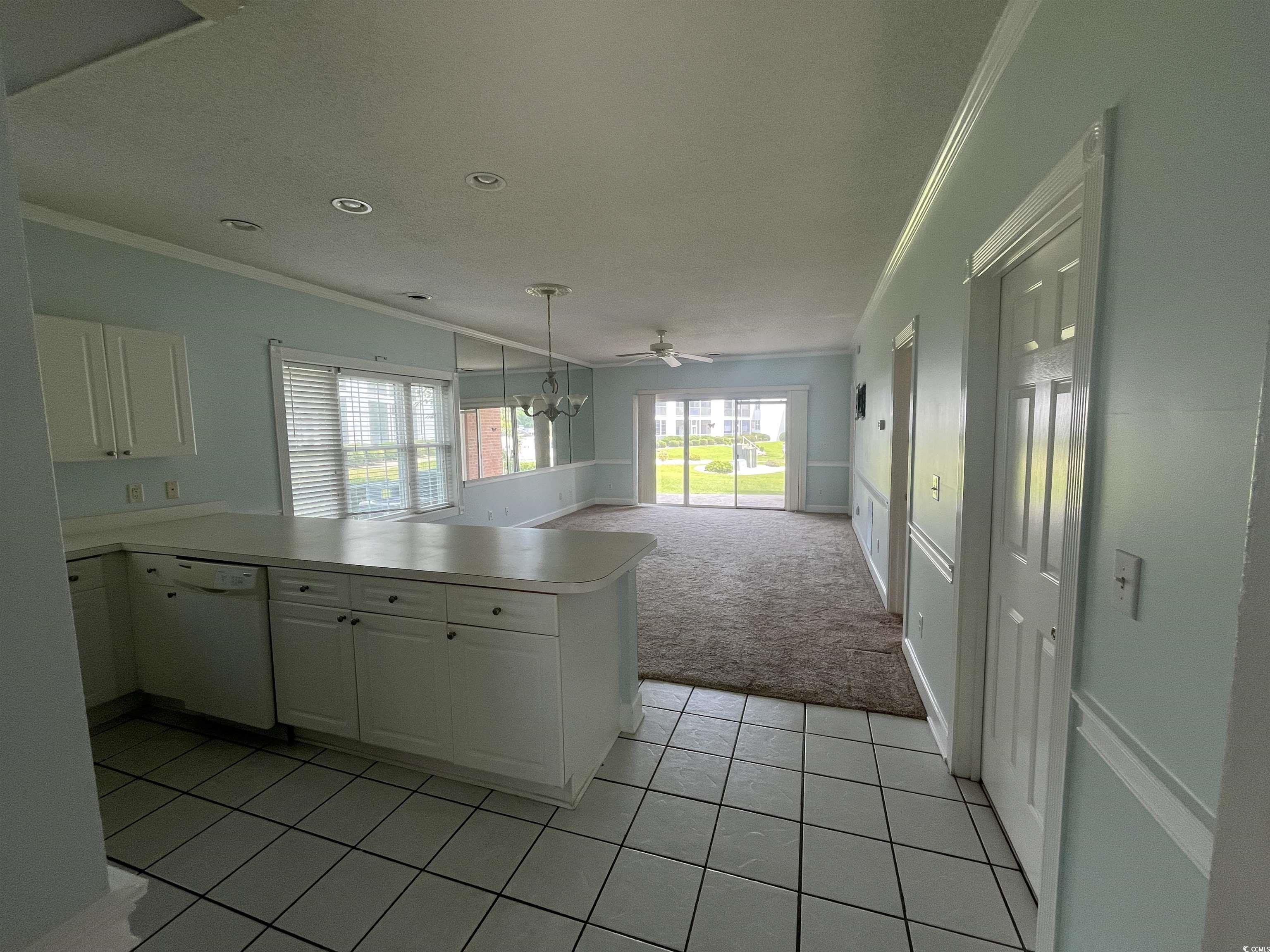 1514 Lanterns Rest Road, Unit 101 Myrtle Beach, SC 29579 - Photo 5 of 20 Kitchen with white dishwasher, crown molding, light colored carpet, a peninsula, and white cabinets