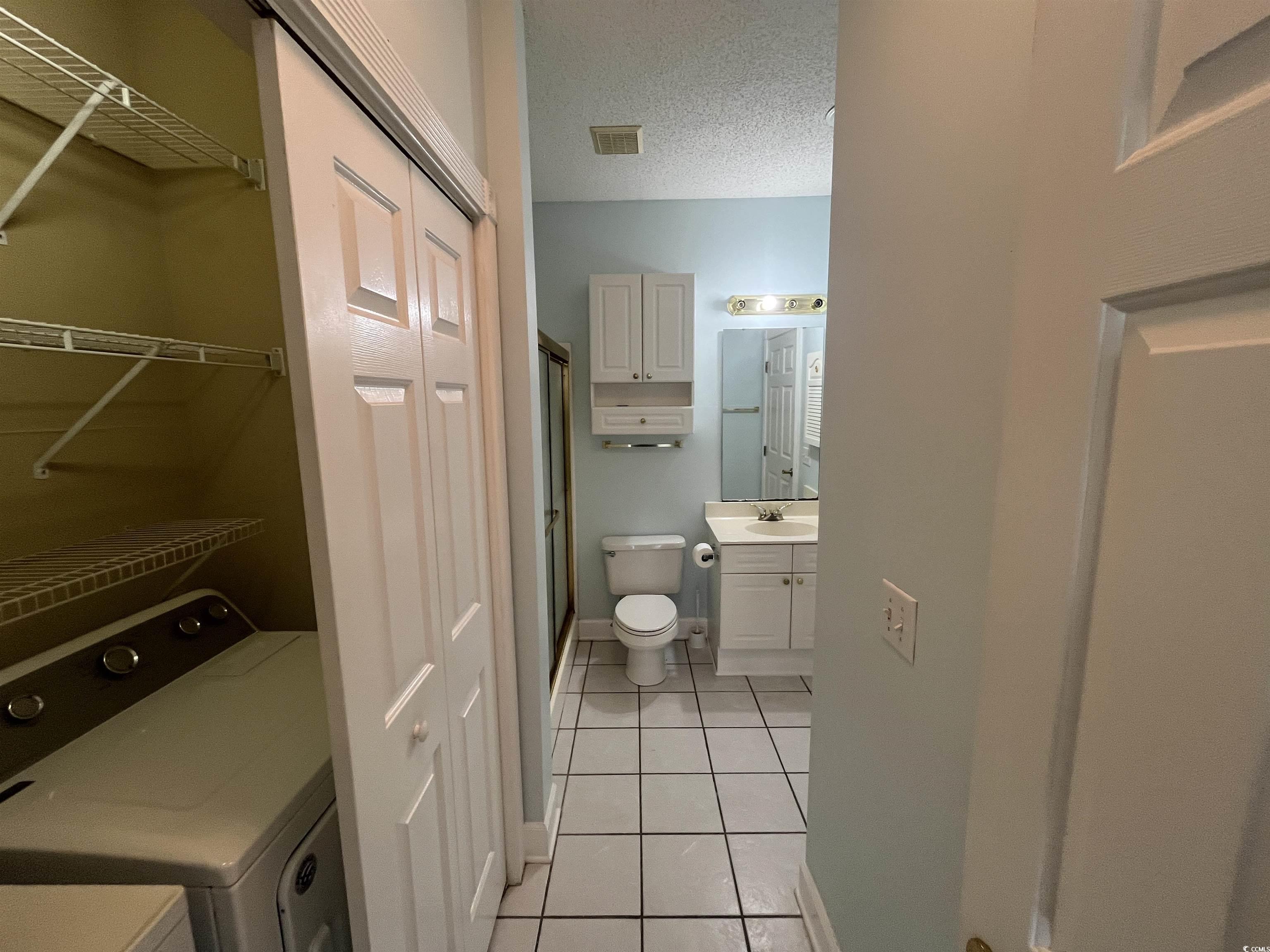 1514 Lanterns Rest Road, Unit 101 Myrtle Beach, SC 29579 - Photo 8 of 20 Full bath with vanity, a stall shower, tile patterned flooring, independent washer and dryer, and a spacious closet