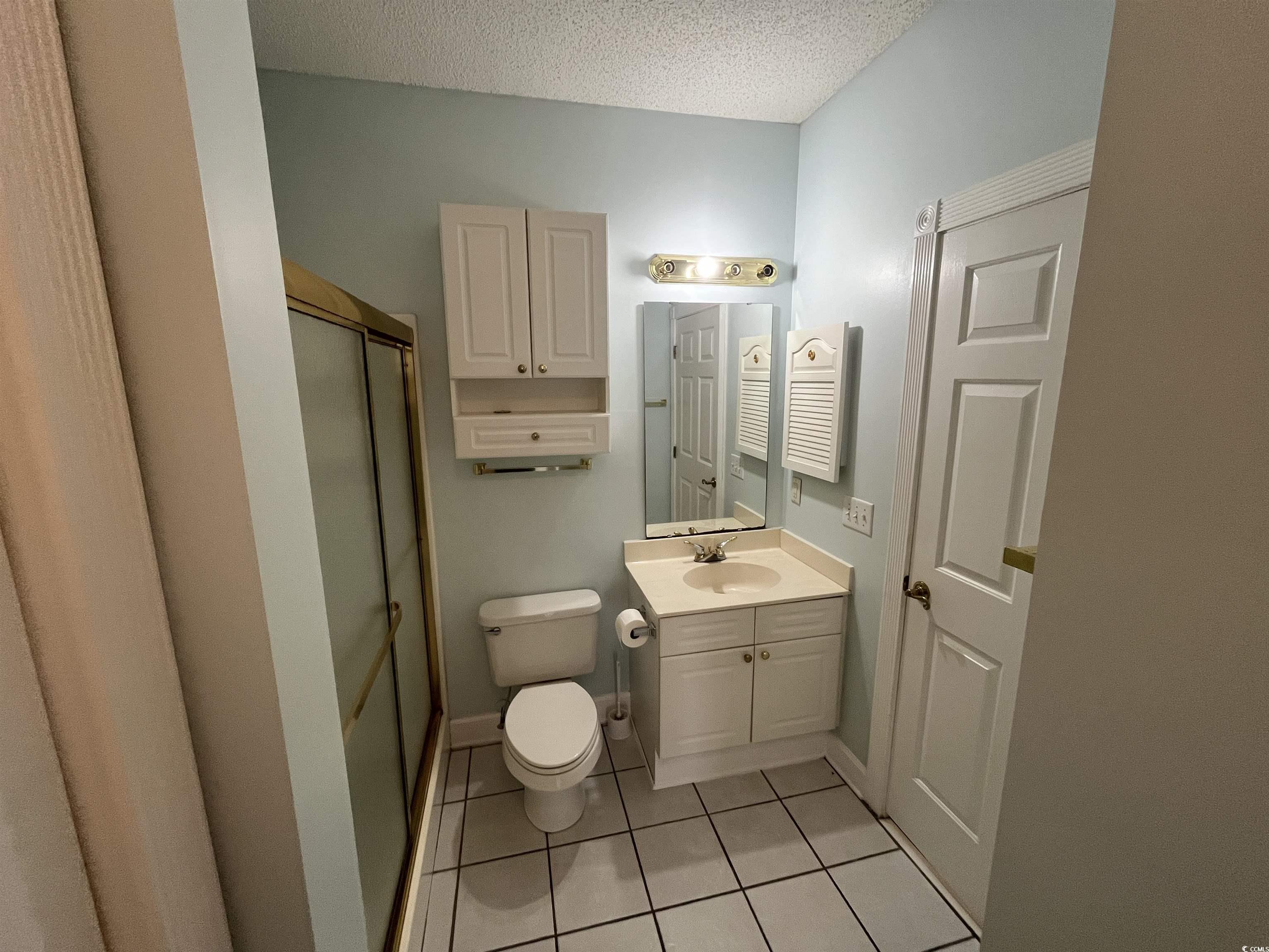 1514 Lanterns Rest Road, Unit 101 Myrtle Beach, SC 29579 - Photo 10 of 20 Full bath with tile patterned floors, vanity, a textured ceiling, and a stall shower