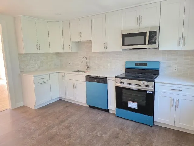 a kitchen with granite countertop white cabinets stainless steel appliances and sink
