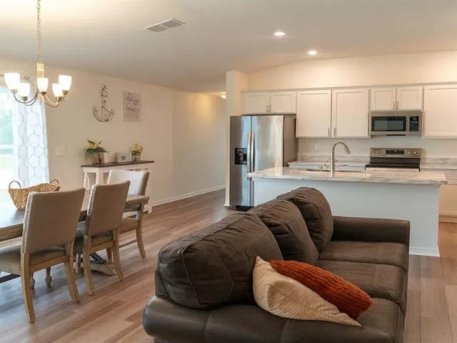 a living room with stainless steel appliances furniture a dining table and a fireplace