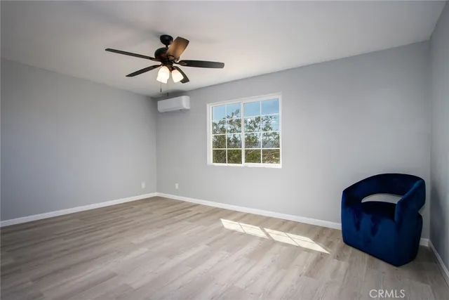 a view of an empty room with window and ceiling fan