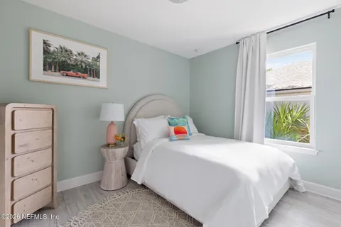 a bedroom with a bed and a chair next to a window