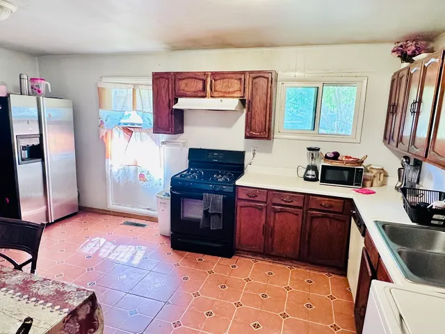 a kitchen with granite countertop a stove a sink and a refrigerator