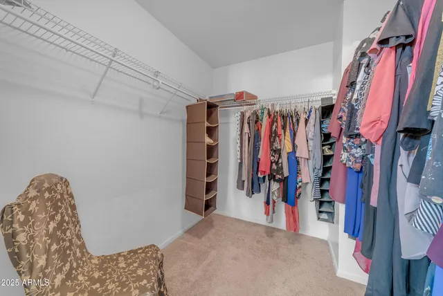 a view of walk in closet with clothes and shoes